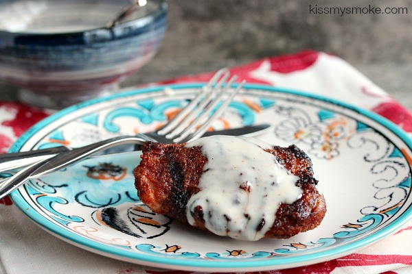 Slow Grilled Chicken Thighs with Alabama White Sauce served on a white and blue plate
