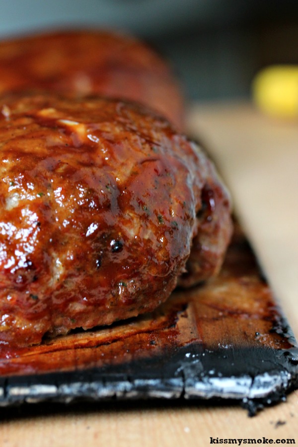 Grilled Meatloaf resting on a wood plank.