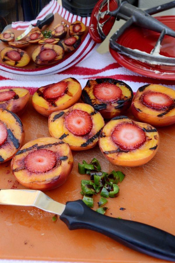 Filling grilled peaches with strawberry halves 