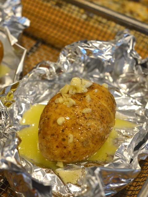 Garlic hasselback potatoes placed in tinfoil and drizzled with butter.
