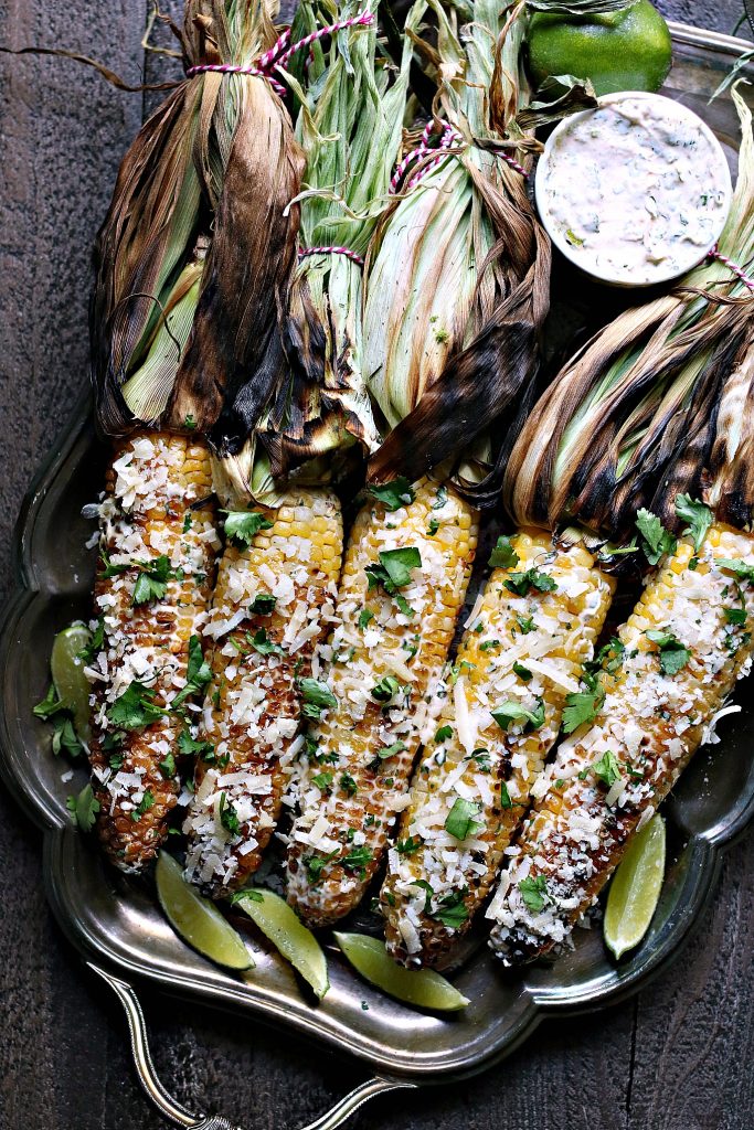 Grilled Mexican Street Corn on a silver platter serves with extra sauce 